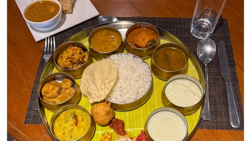 Thali indio con arroz, panes y varios curries servidos en cuencos metalicos