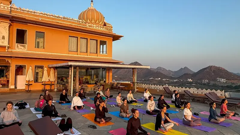 Grupo practicando yoga y meditacion al amanecer en la terraza de un palacio en la India