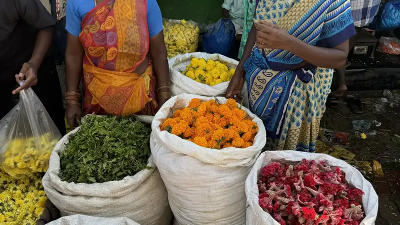 Vendedoras junto a sacos de petalos de rosa y calendula en el mercado de flores de Madurai, Tamil Nadu