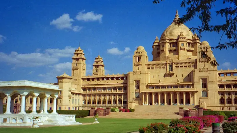 Hotel palacio en Rajastán, India: cúpulas y fachada de mármol reflejadas en el lago al atardecer, viaje de lujo estilo maharajá
