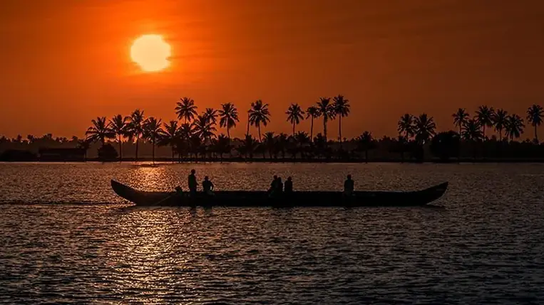 Canoa tradicional recortada contra el atardecer en los backwaters de Kerala