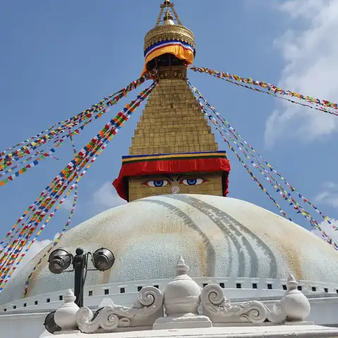 Los ojos pintados y la torre dorada de la estupa de Boudhanath bajo banderas de oración, Katmandú