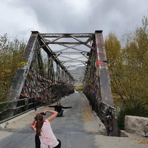 Viajera fotografiando el paisaje desde un puente de hierro en Ladakh