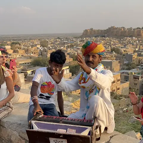 Dos músicos tocan sobre la muralla del fuerte de Jaisalmer al atardecer, con la ciudad dorada a sus pies