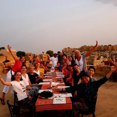 Grupo de viajeros cenando al atardecer en un campamento del desierto de Rajastán
