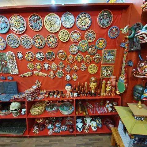 Tienda de artesanía butanesa con máscaras de madera, platos pintados y figuras rituales en las paredes rojas