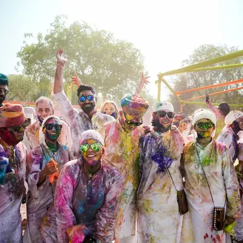Viajeros y guías cubiertos de pigmentos de colores celebrando el festival de Holi en la India