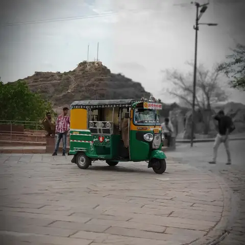 Un tuk-tuk circula frente a un fuerte de Jodhpur, fotografía en blanco y negro