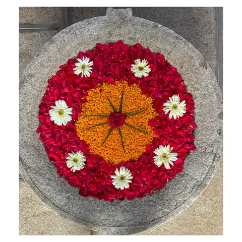 Rangoli circular de pétalos de rosa, caléndula y flores blancas sobre un suelo de piedra en el sur de la India
