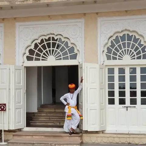 Hombre con turbante de pie ante la gran puerta ornamentada de un fuerte en Jodhpur, Rajastán