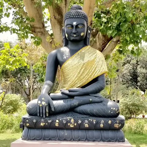Estatua negra y dorada del Buda en meditación bajo un árbol en Sarnath, cerca de Varanasi