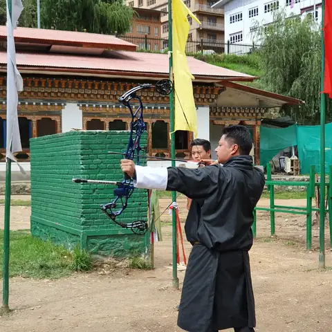 Hombre en traje tradicional butanés practicando tiro con arco, el deporte nacional de Bután