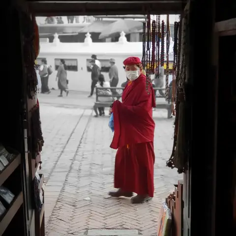 Monje budista visto a través del vano de una puerta junto a la estupa de Boudhanath, Katmandú