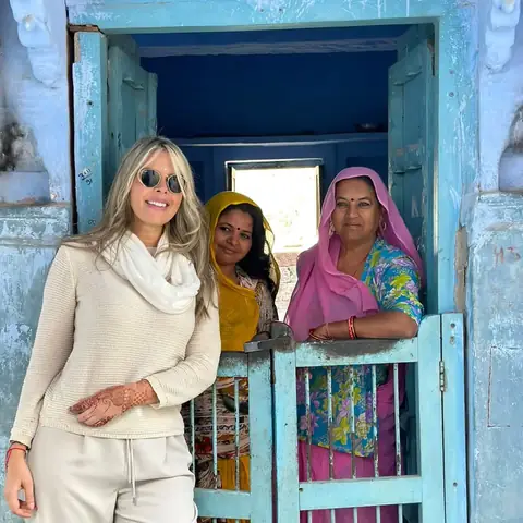 Viajera junto a dos mujeres locales en la puerta azul de una casa en Rajastán