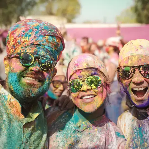Pareja de viajeros cubiertos de polvo de color, sonriendo durante el festival Holi