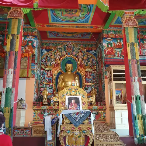 Altar profusamente decorado con un Buda dorado, columnas pintadas y sedas en un monasterio budista del Himalaya