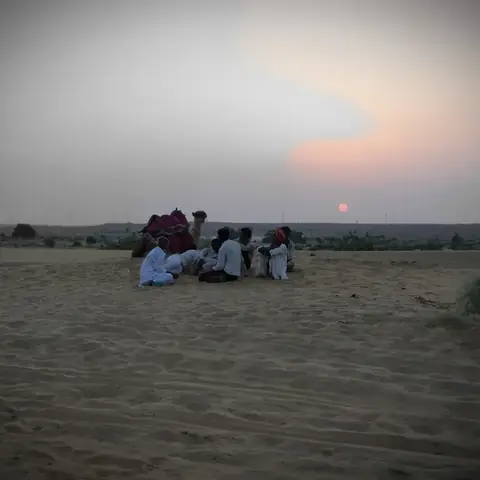 Grupo de camellos y guías en silueta contra el atardecer en el desierto de Rajastán