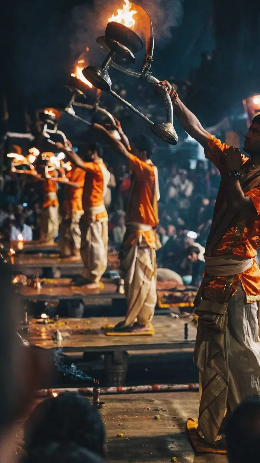 Sacerdotes alzan lámparas encendidas durante el aarti del Ganges, al anochecer en Varanasi