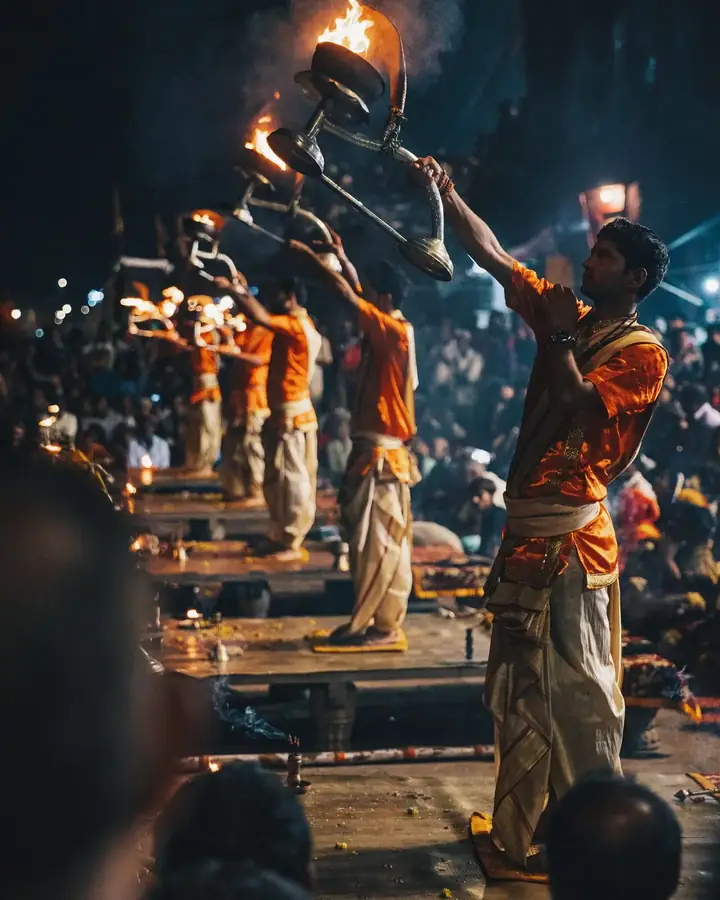 Sacerdotes alzan lámparas encendidas durante el aarti del Ganges, al anochecer en Varanasi